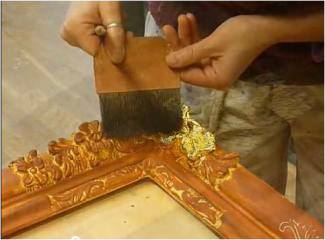 Photo showing the application of gold leaf on the corner of an ornate picture frame