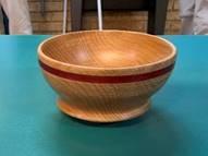 Photo of Allan's first attempt a turning a bowl. The bowl features a ring of red inlaid twine as a feature.